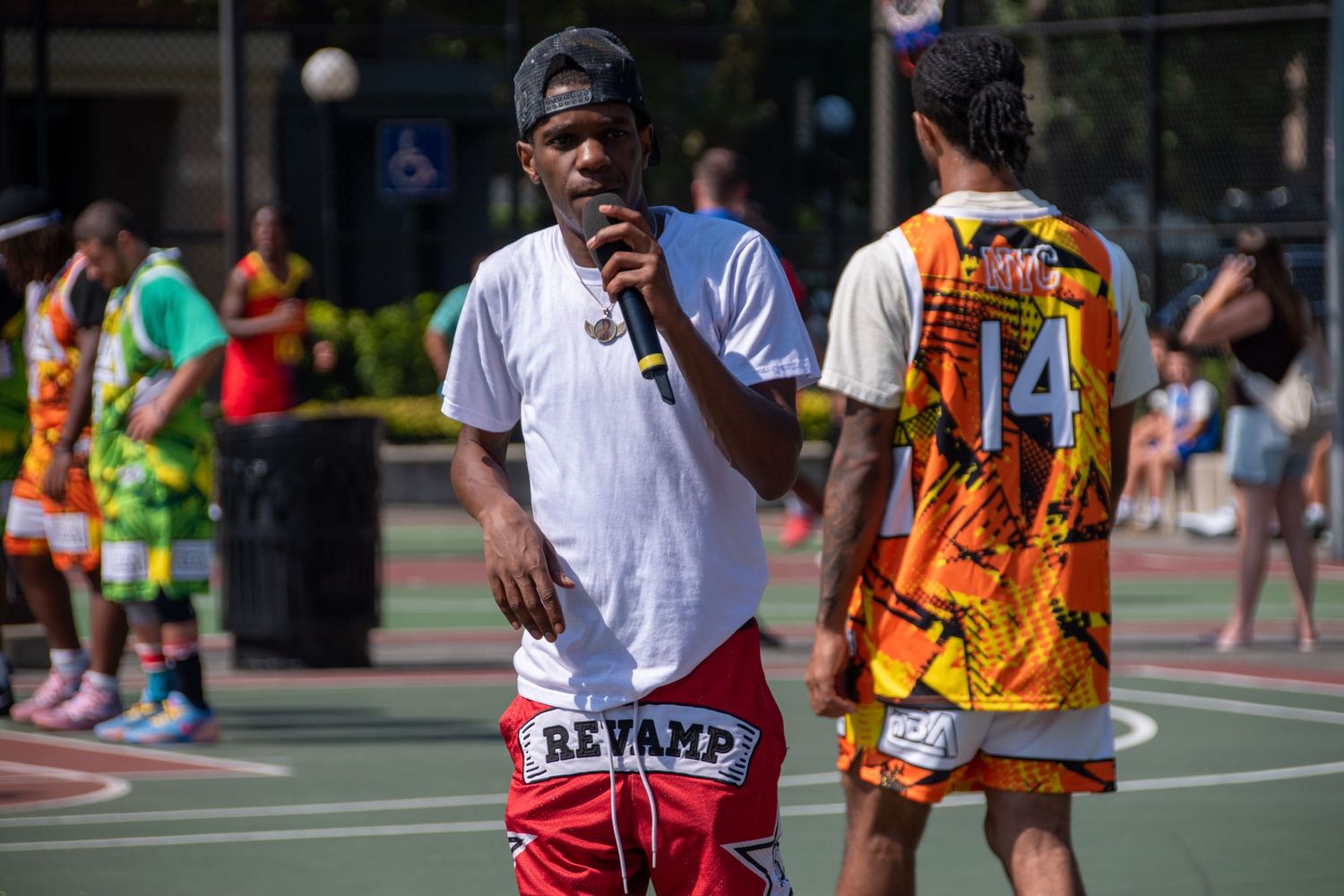 Two people talking during a streetball tournament on an outdoor basketball court.
