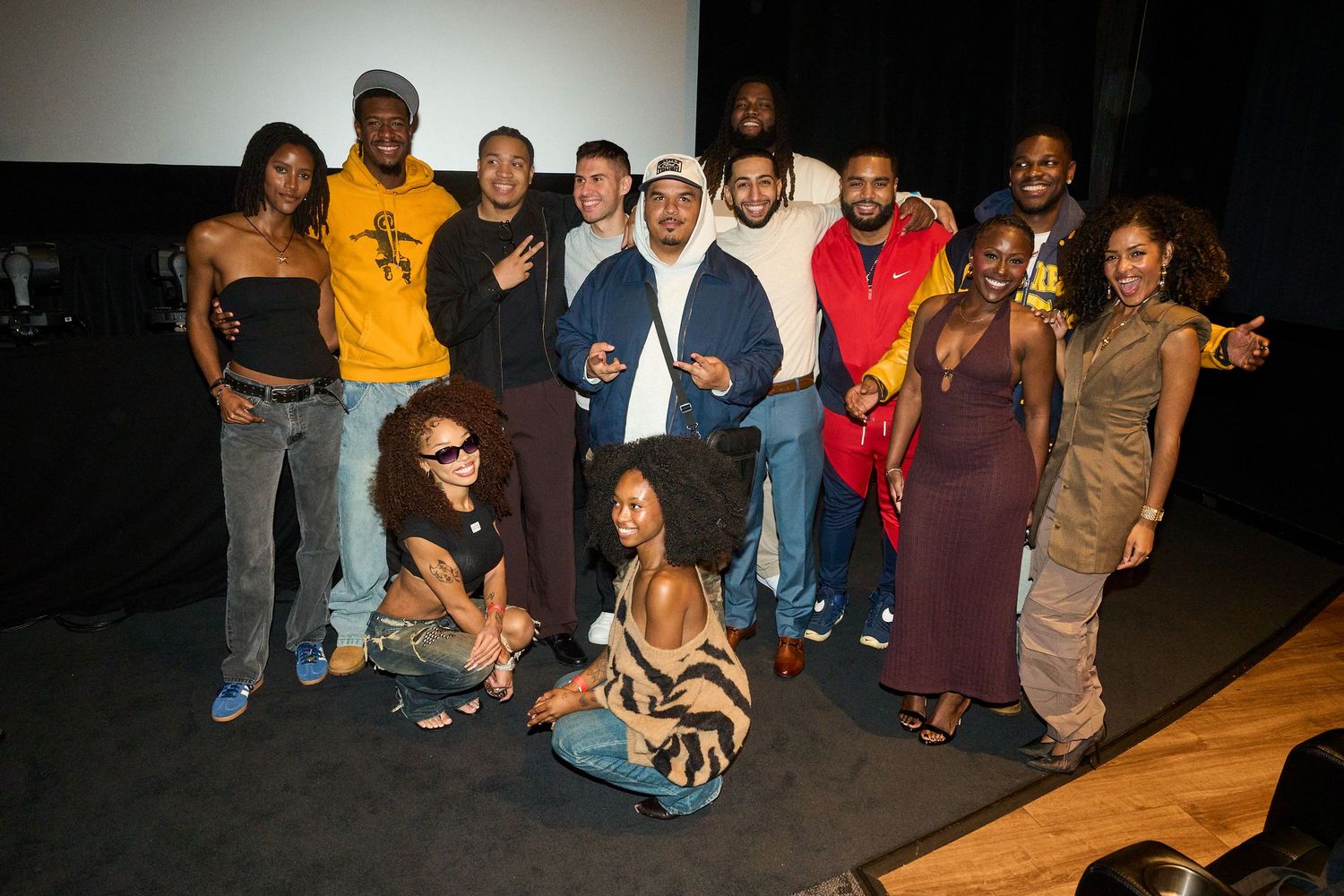 A diverse group of people posing together for a photo at an indoor event near a stage.