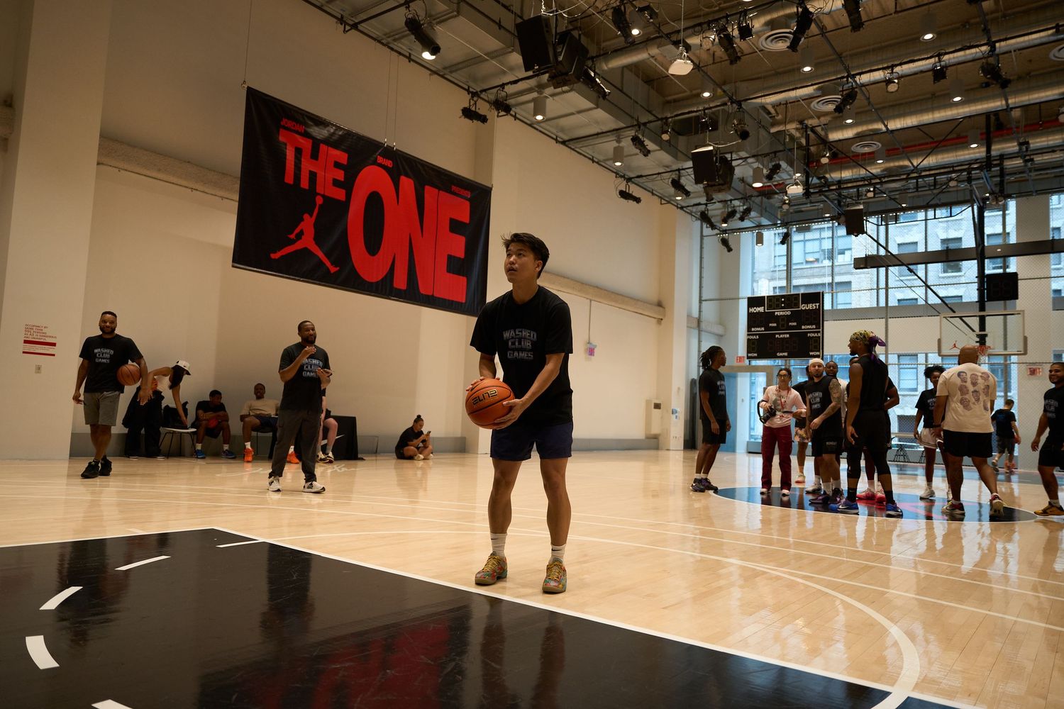 Basketball players practicing drills and running exercises on a bright indoor court with white walls.