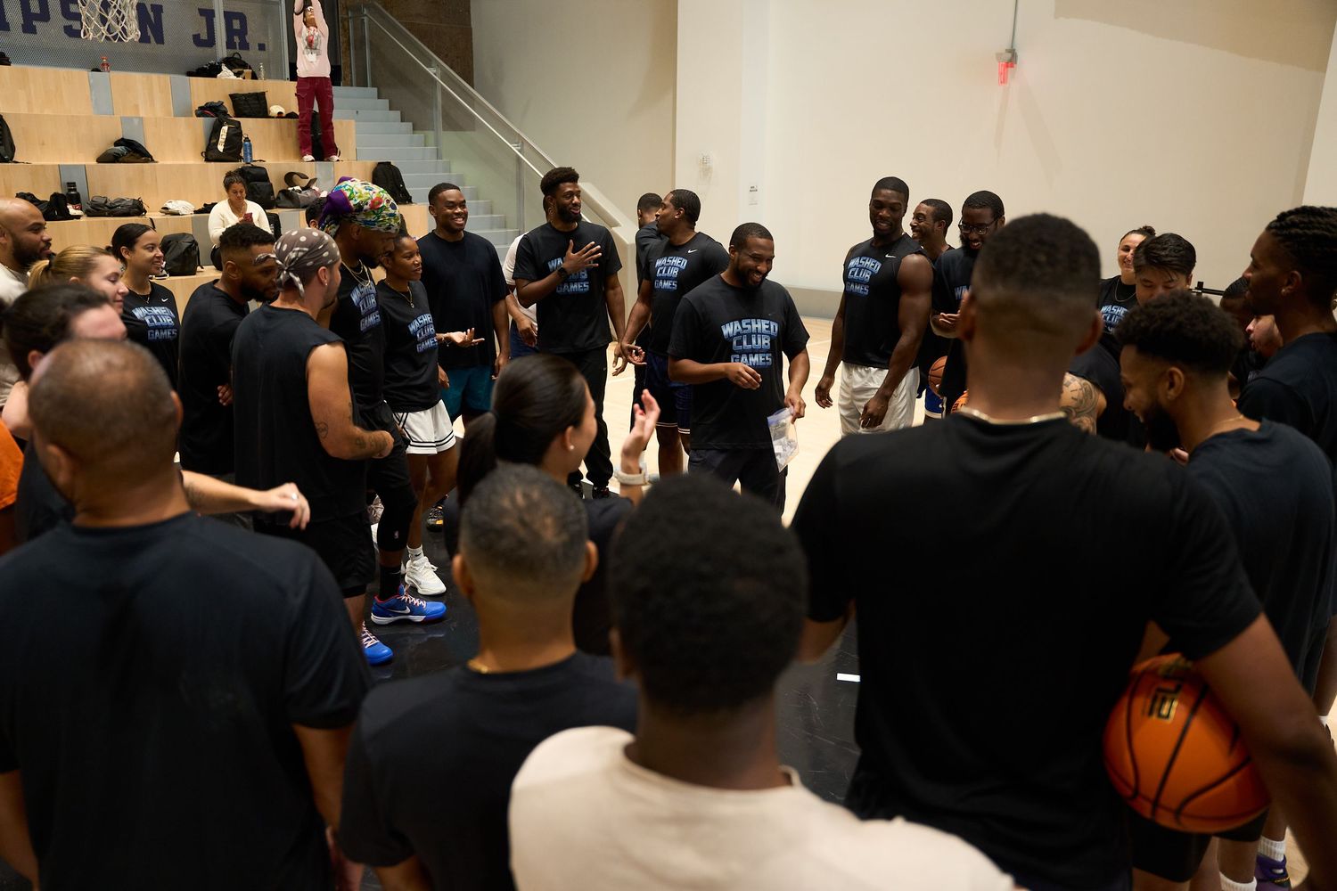 A large crowd of people dressed in black gather in what appears to be a hallway or indoor venue.