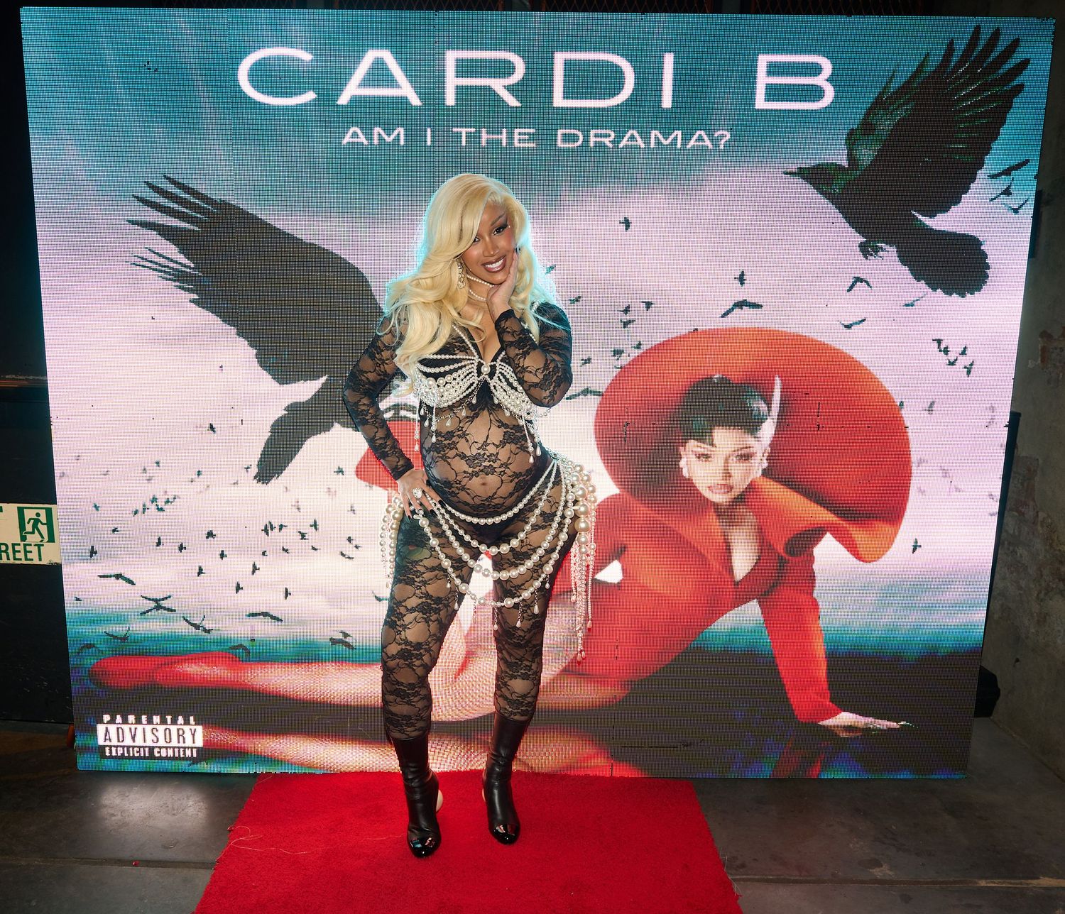 Concert performer in red outfit on stage with dramatic lighting and visual effects during live performance.