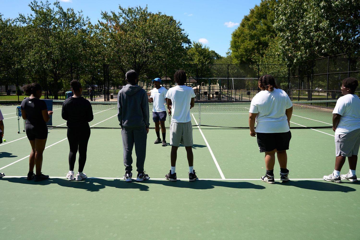 Large group of students gathered on an outdoor tennis court for a school event or activity.