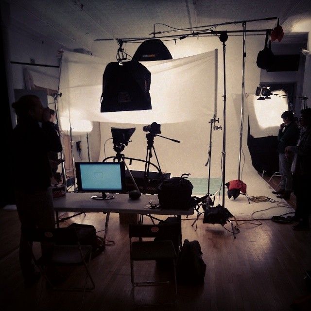 Professional photography studio setup with lights, reflectors and equipment arranged on stands against a white backdrop.