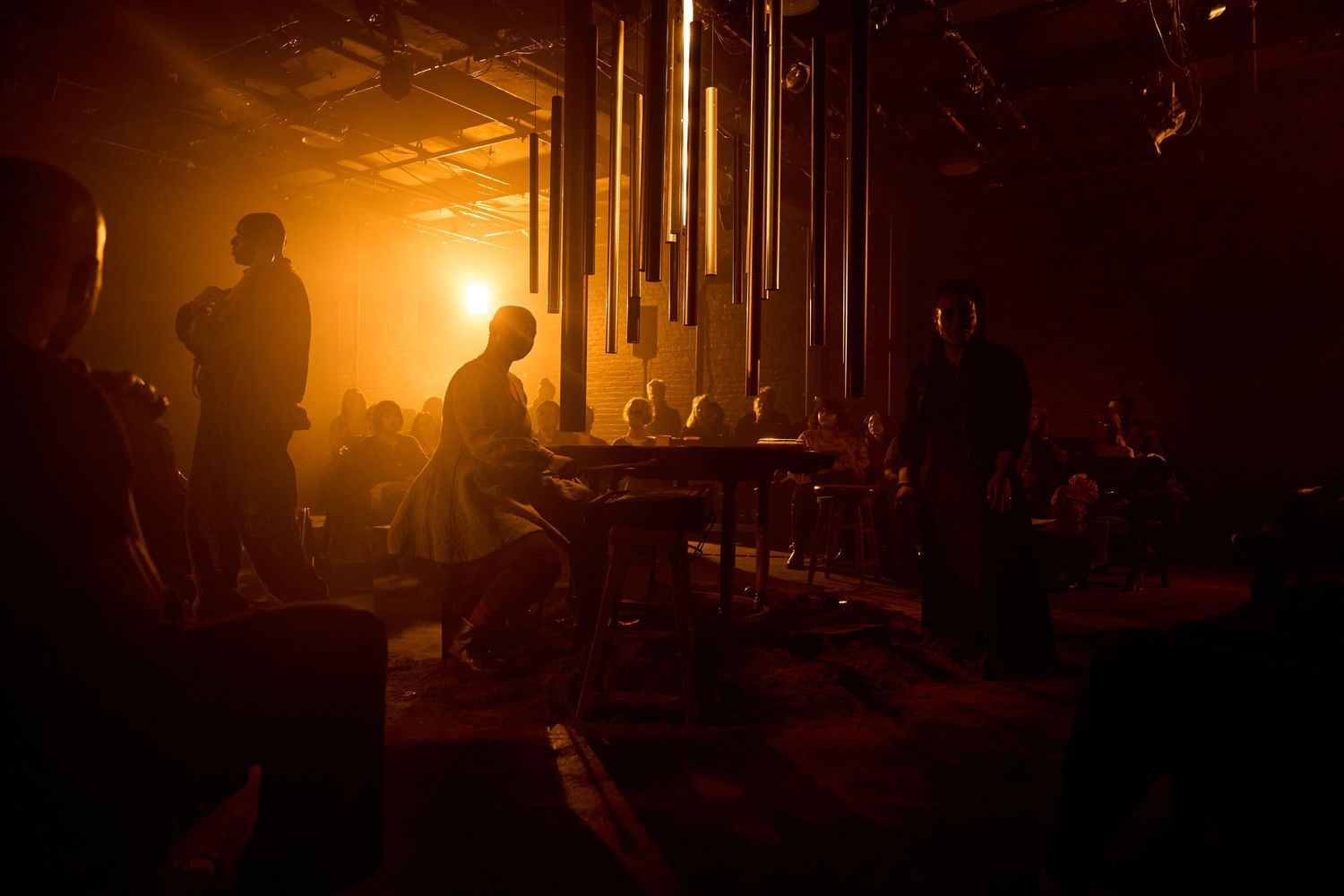 Silhouettes of people dancing in a dimly lit nightclub with warm orange lighting creating an atmospheric ambiance.