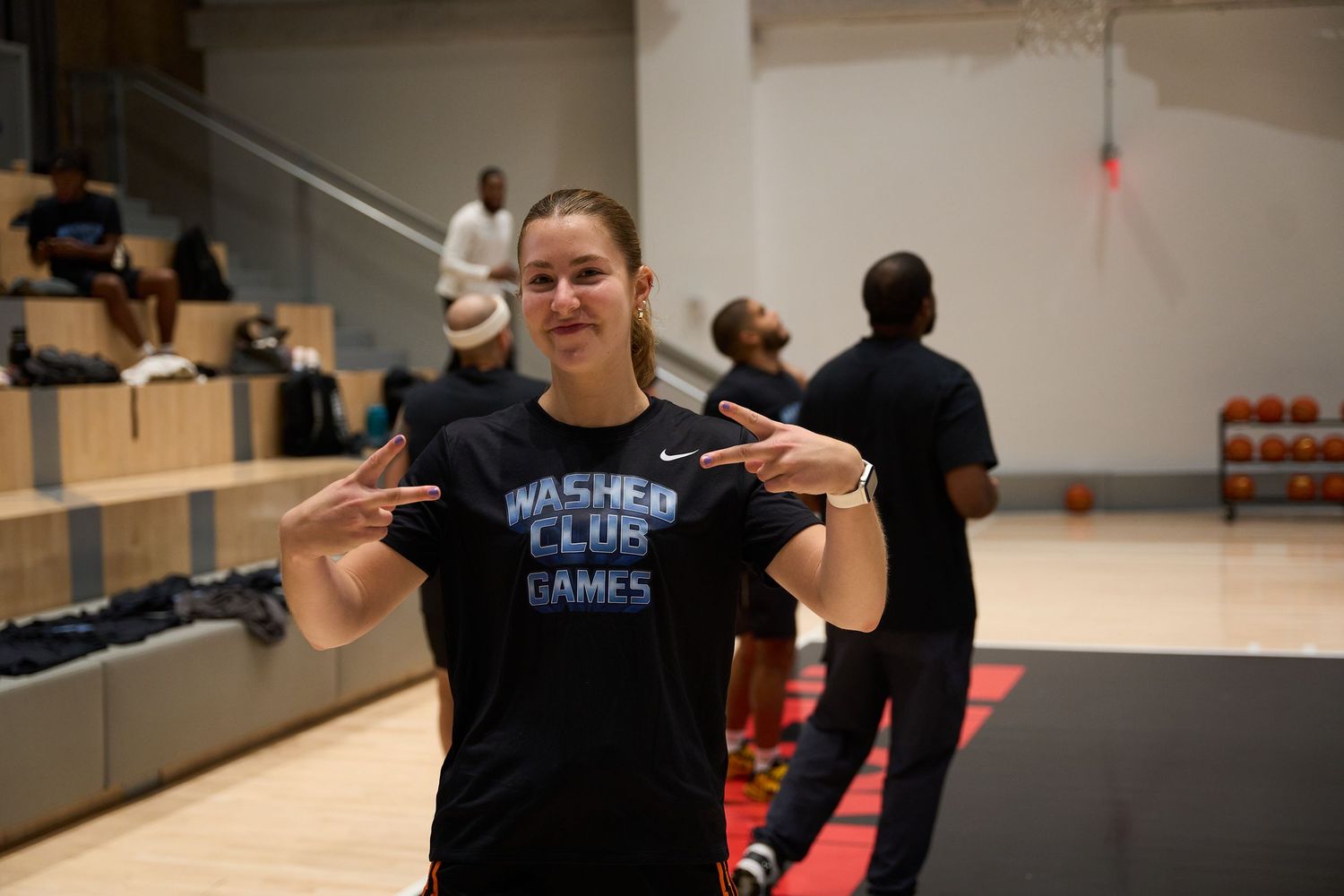 Athletes participate in a training session at an indoor basketball facility while wearing masks.