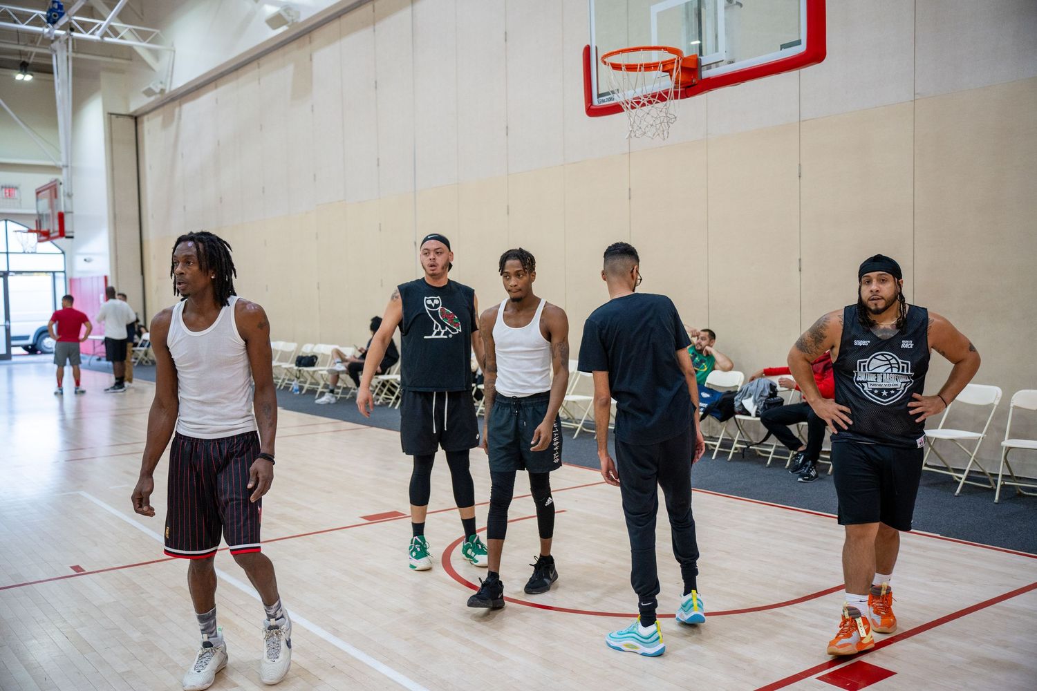 Players gather on an indoor basketball court during a casual game at a community gym.