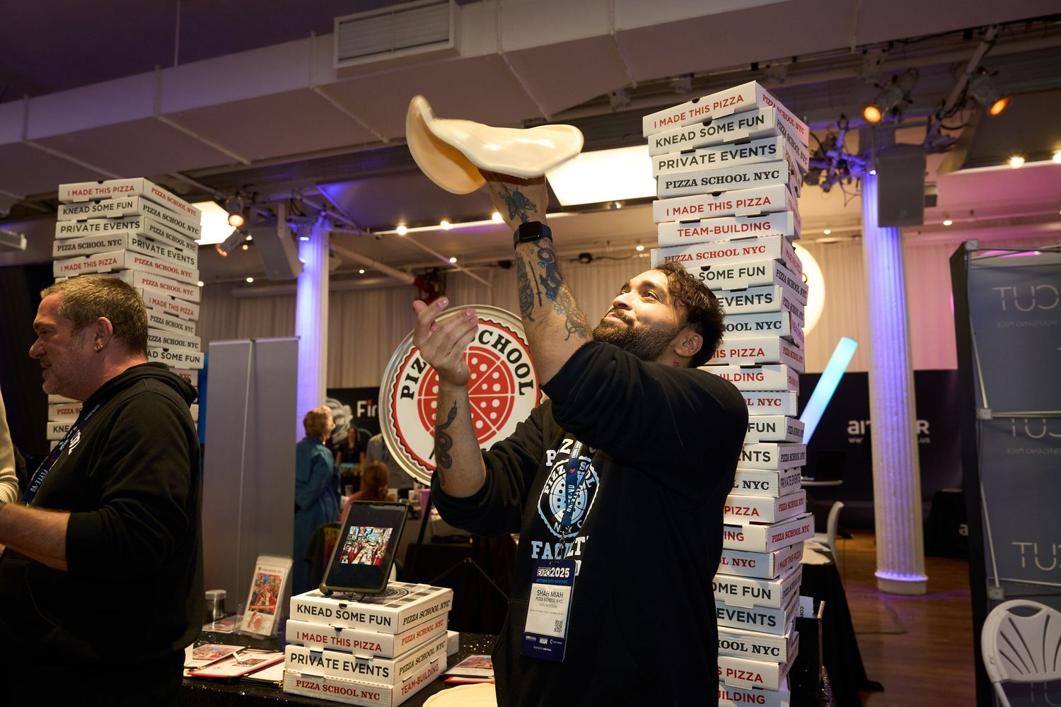 A person holds multiple pizza boxes while standing in front of a counter at a pizza restaurant.