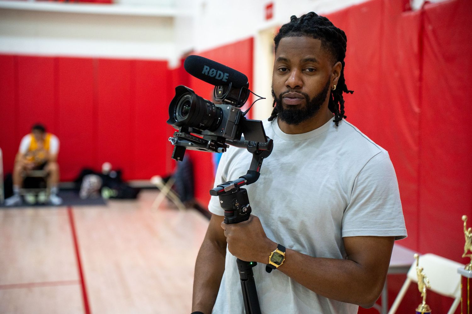 A professional boxer trains with focus mitts during an intense workout session in a red-walled gym.