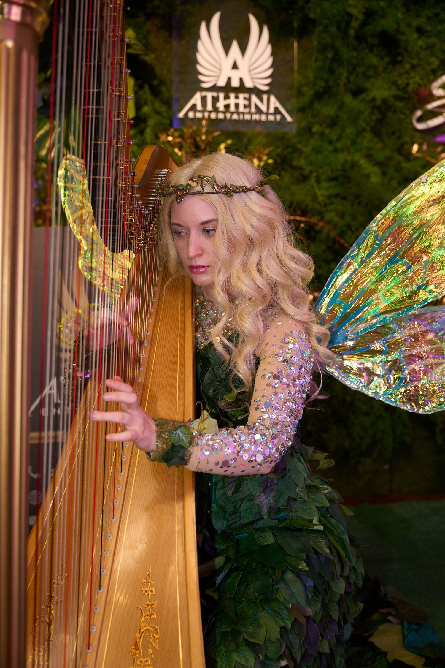 Harpist in a sparkly costume with fairy wings performs on stage at the Athena venue.
