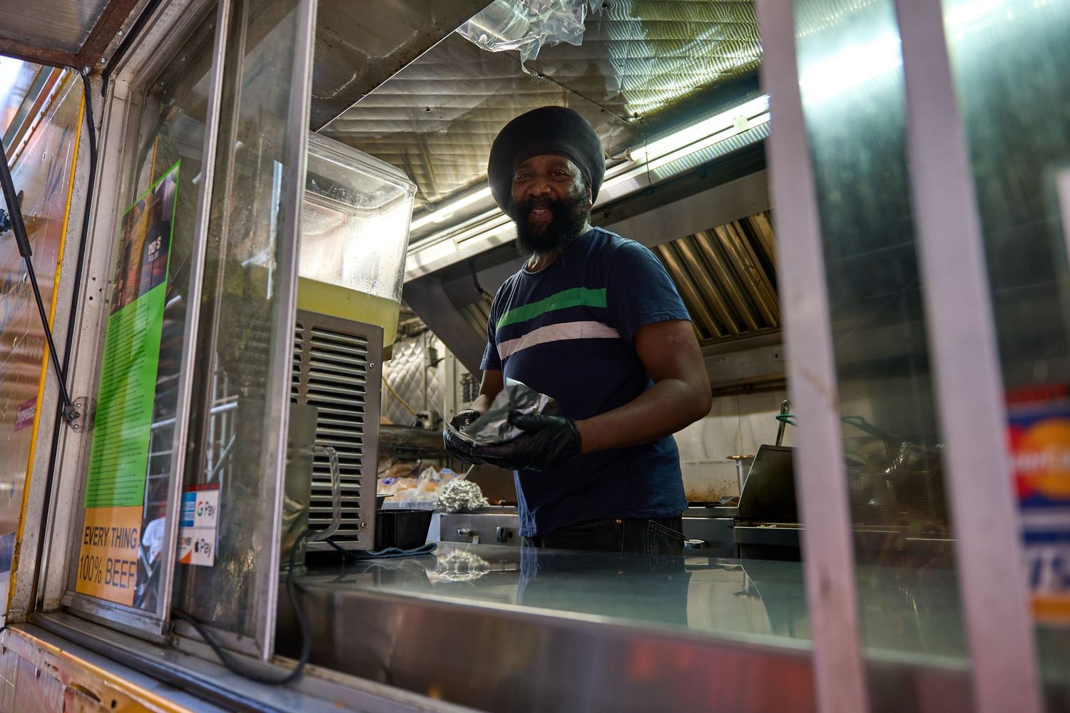 Street food vendor preparing delicious meals in a mobile food cart with steam rising from cooking surfaces.