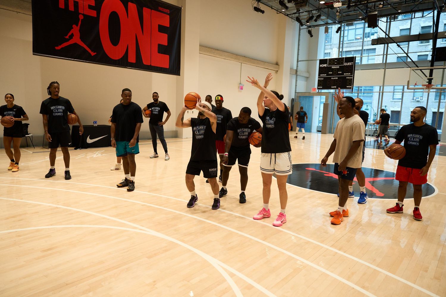 Indoor basketball court with red signage on wall showing players participating in practice drills.