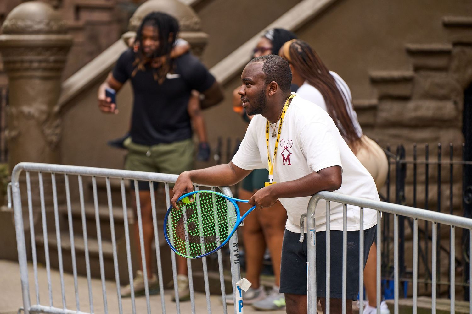 A group of people gather around a railing during what appears to be a social or community event outdoors.