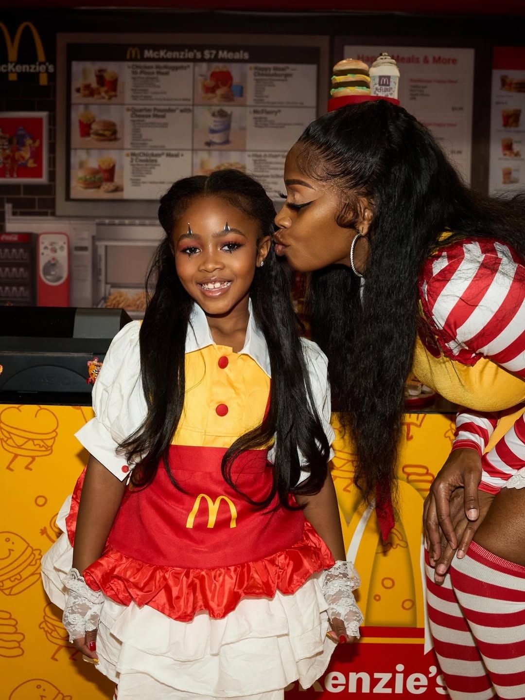 A group of people in McDonald's uniforms with red and white striped shirts and yellow accents pose together.