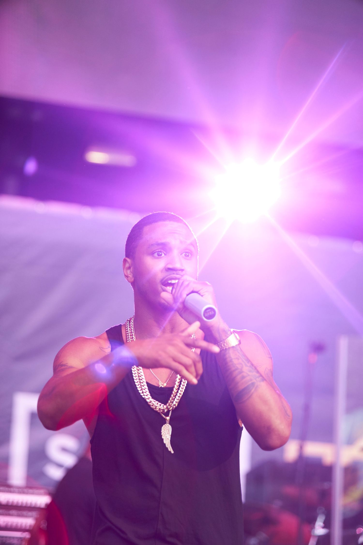 Performer singing on stage with bright purple stage lighting and atmospheric effects creating a dramatic concert atmosphere.