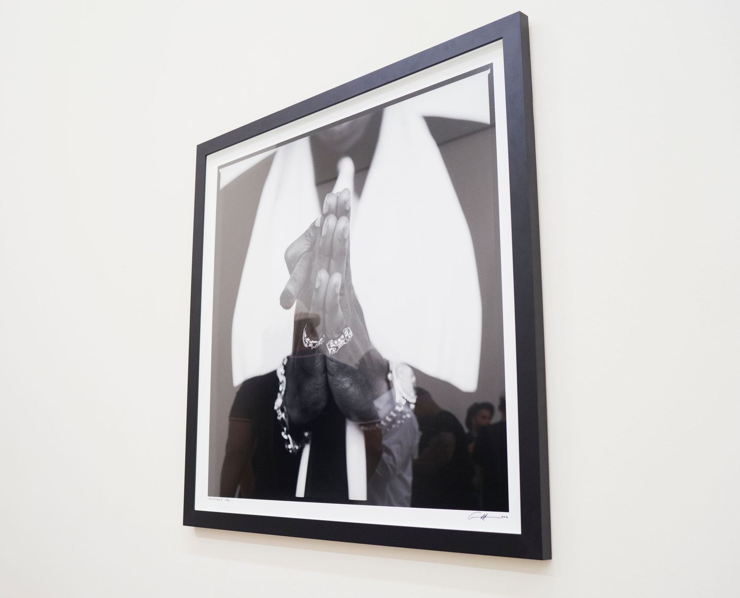 Framed black and white art photograph showing dramatic silhouettes with a triangle pattern hung on a white wall.