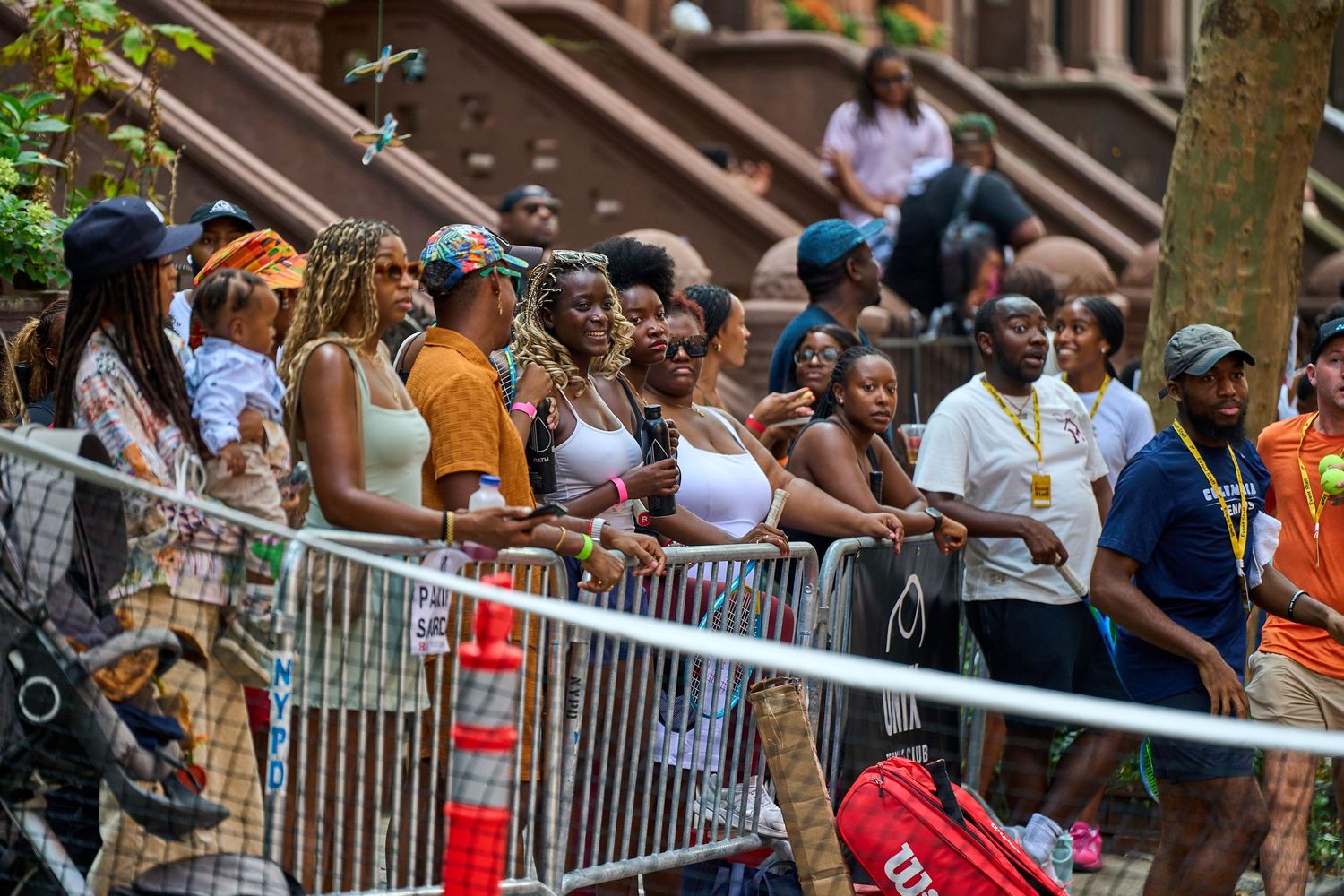 Spectators gather behind metal barricades along a street during a public event.