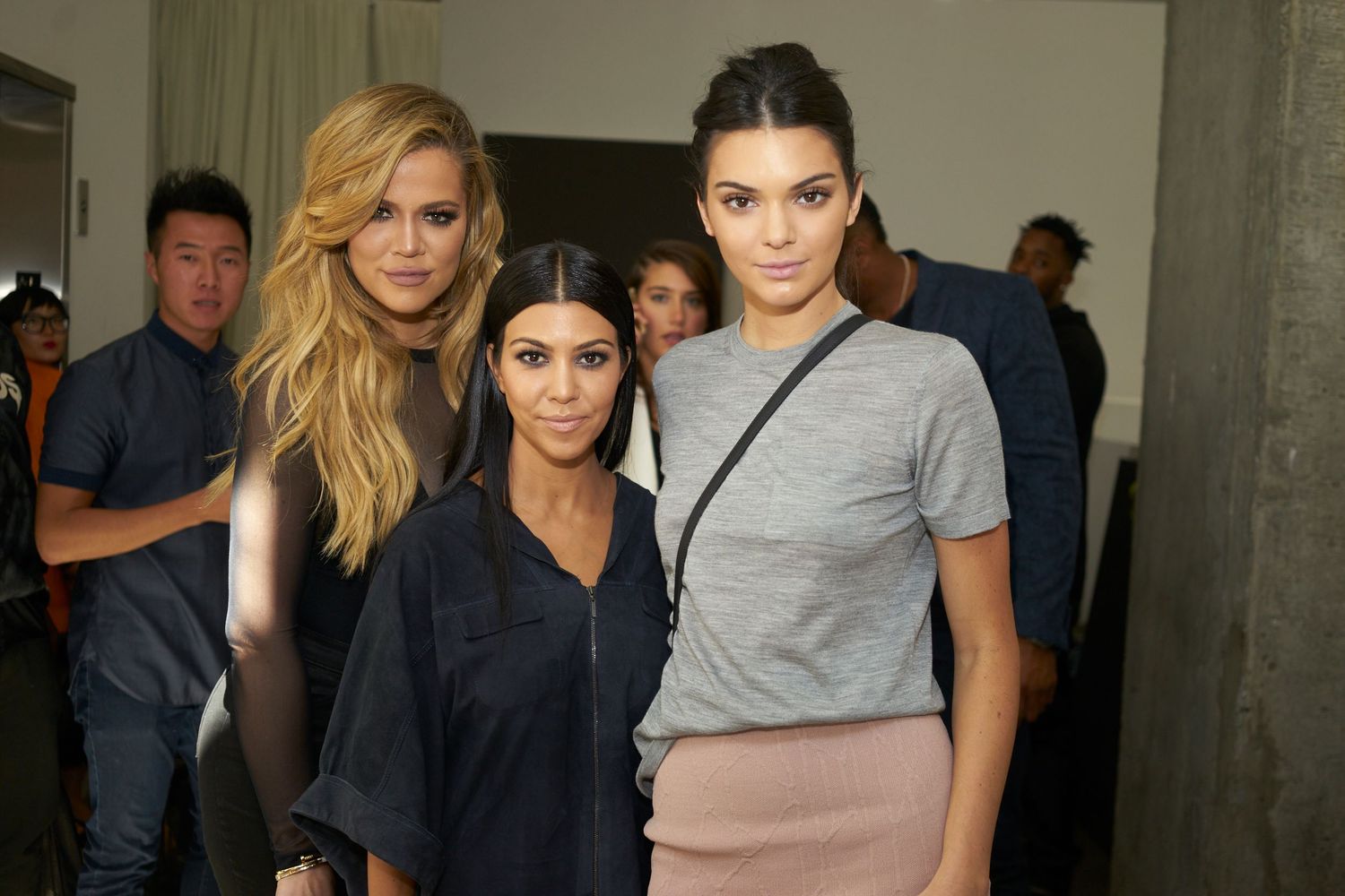 Three people in stylish casual outfits pose together backstage at a fashion industry event.