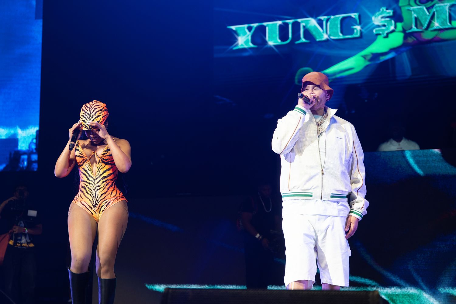 Female performer in tiger print bodysuit on stage with male rapper at Yung Miami show.