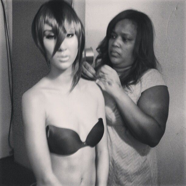 Stylist working on adjusting a mannequin's hair in black and white photography.