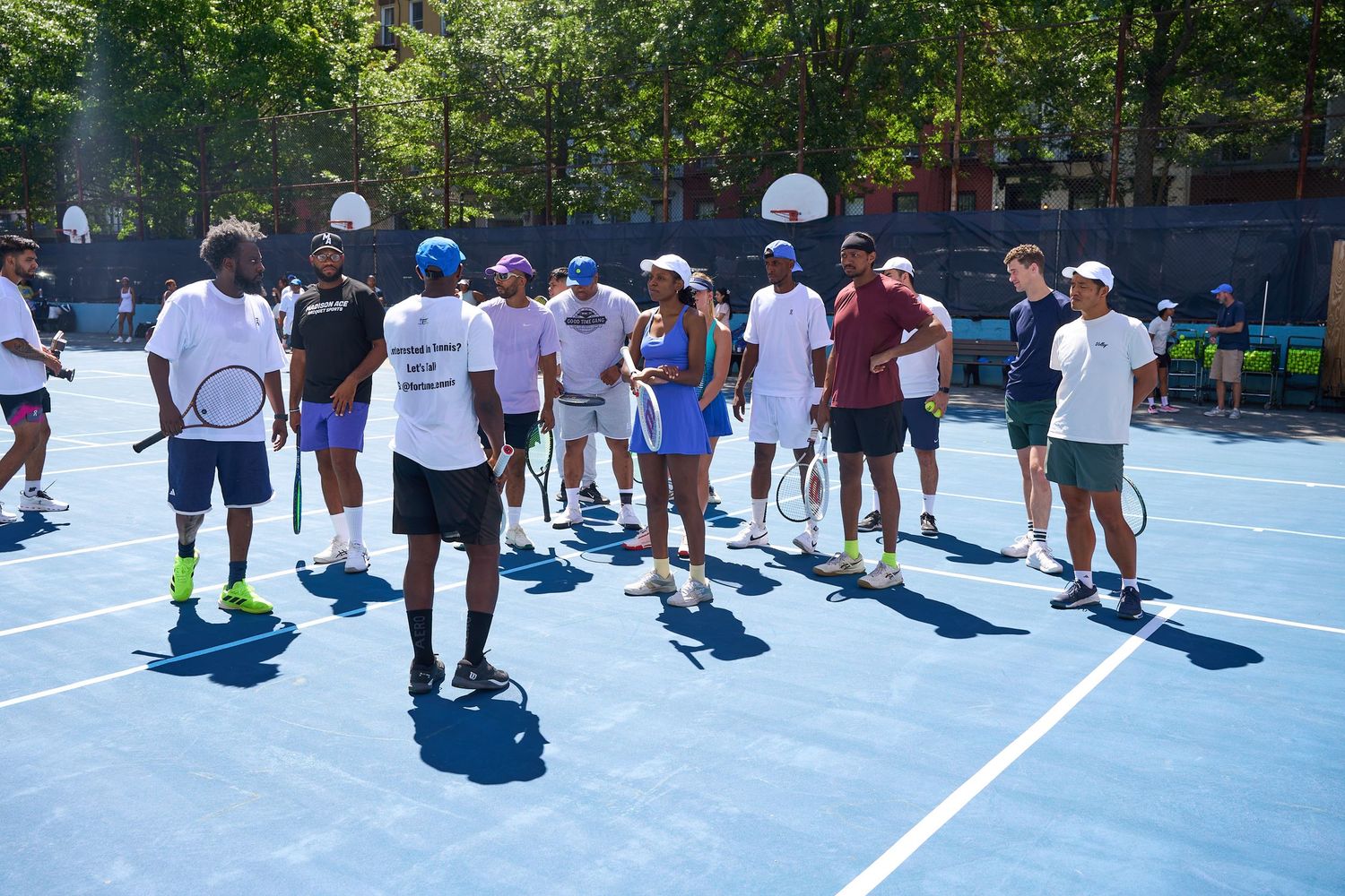 People stand in line on a blue tennis court during a daytime event.