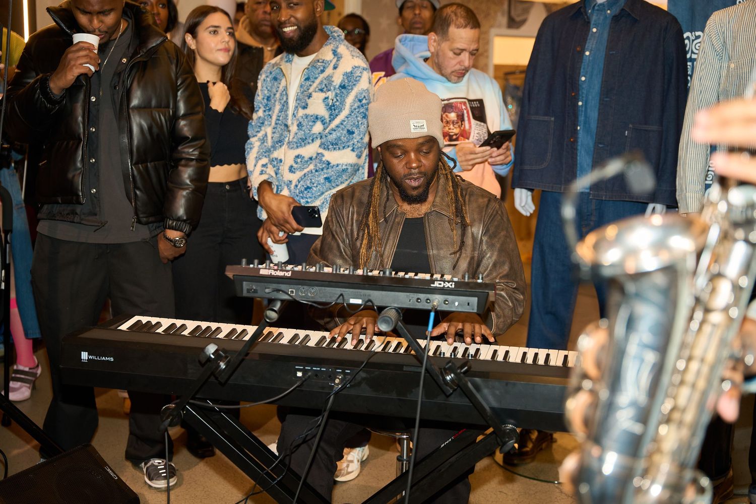 Musicians perform with keyboard and instruments during indoor concert or event.