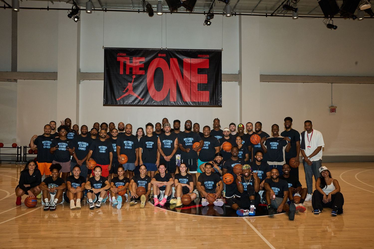 Large group of basketball players and staff wearing matching blue uniforms sit together for team photos in a gymnasium.