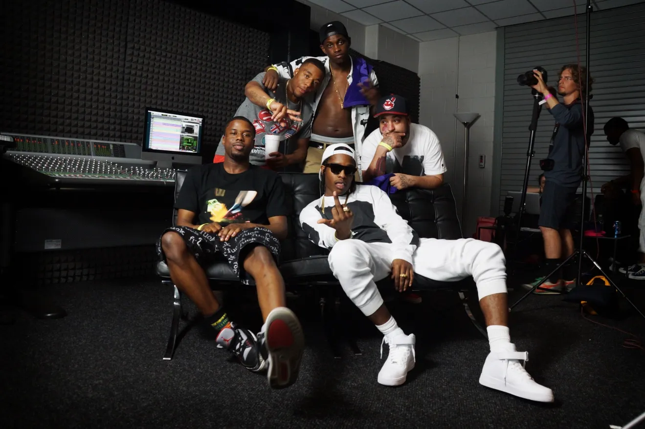 Musicians relaxing and posing together in a recording studio with casual urban style clothing and white sneakers.