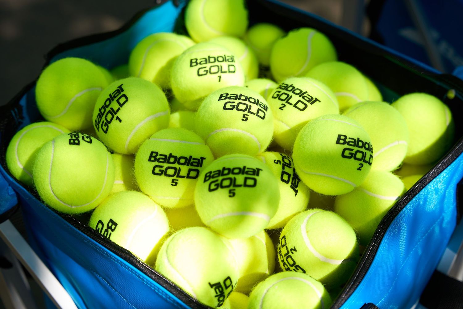 Bright yellow tennis balls packed tightly in blue containers at a sporting event or facility.