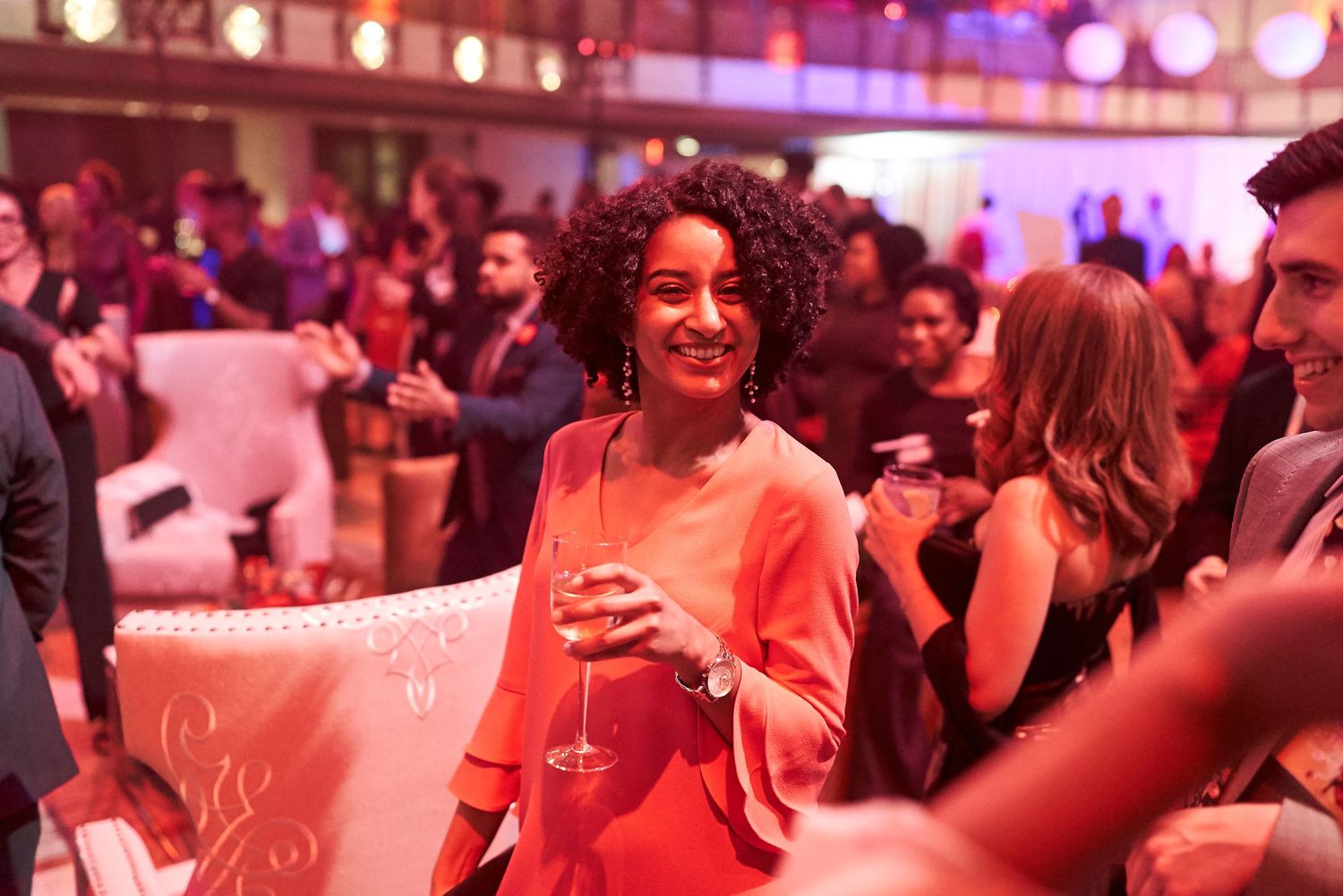 People dancing and enjoying themselves in a nightclub with red ambient lighting and a festive atmosphere.