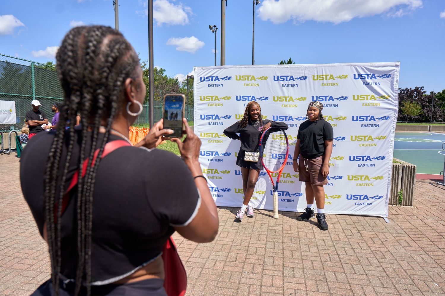 Athletes gather at an outdoor track and field event with banners and signage visible in the background.