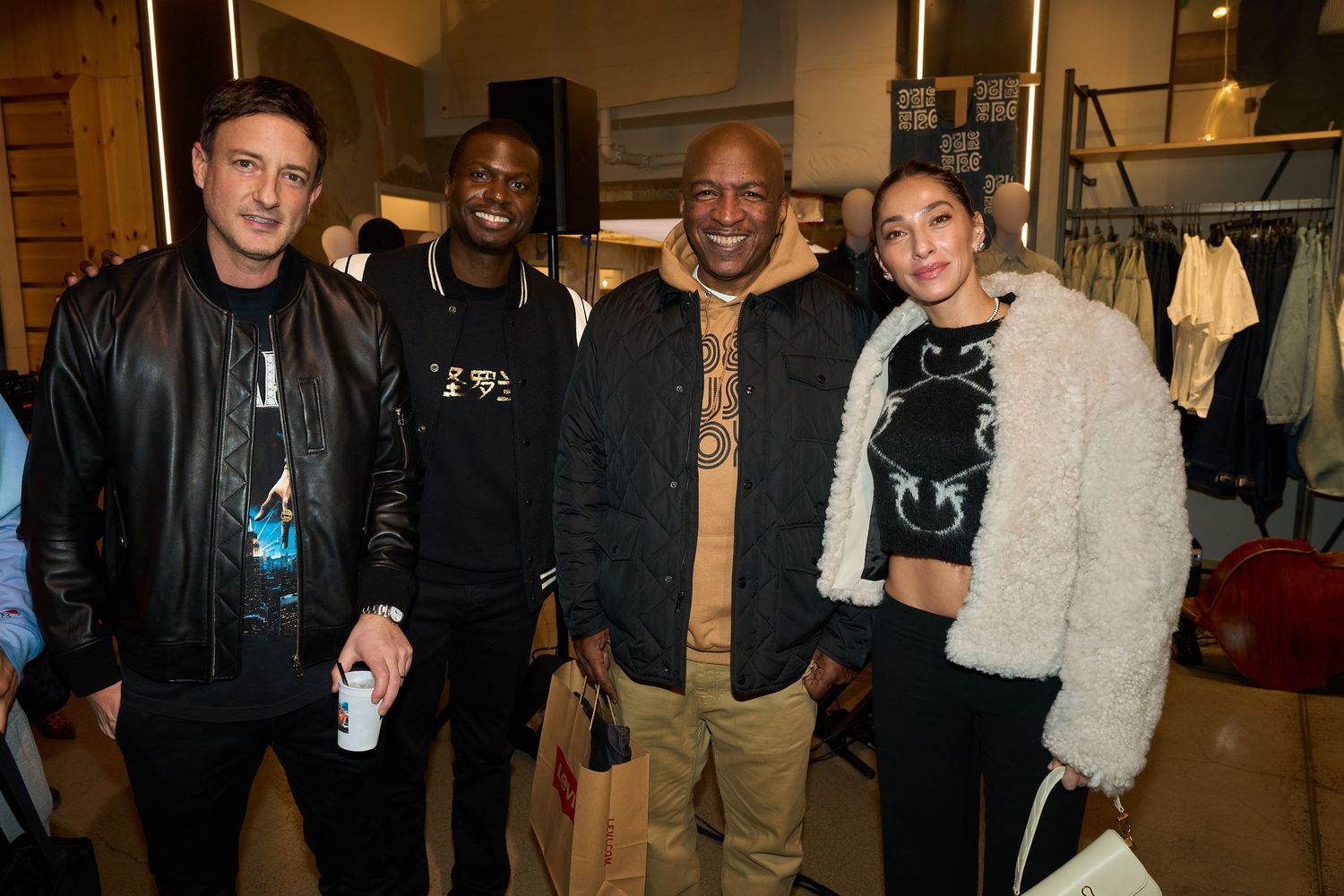 A group of musicians and performers gathered together in what appears to be a backstage or studio setting.