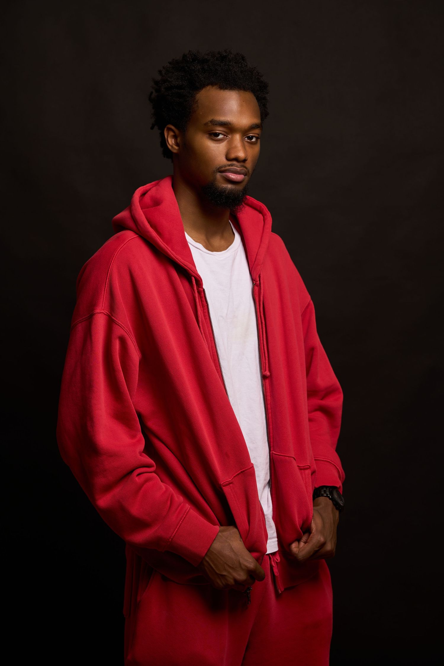 Person wearing a bright red hoodie and white t-shirt poses against dark background in multiple shots.