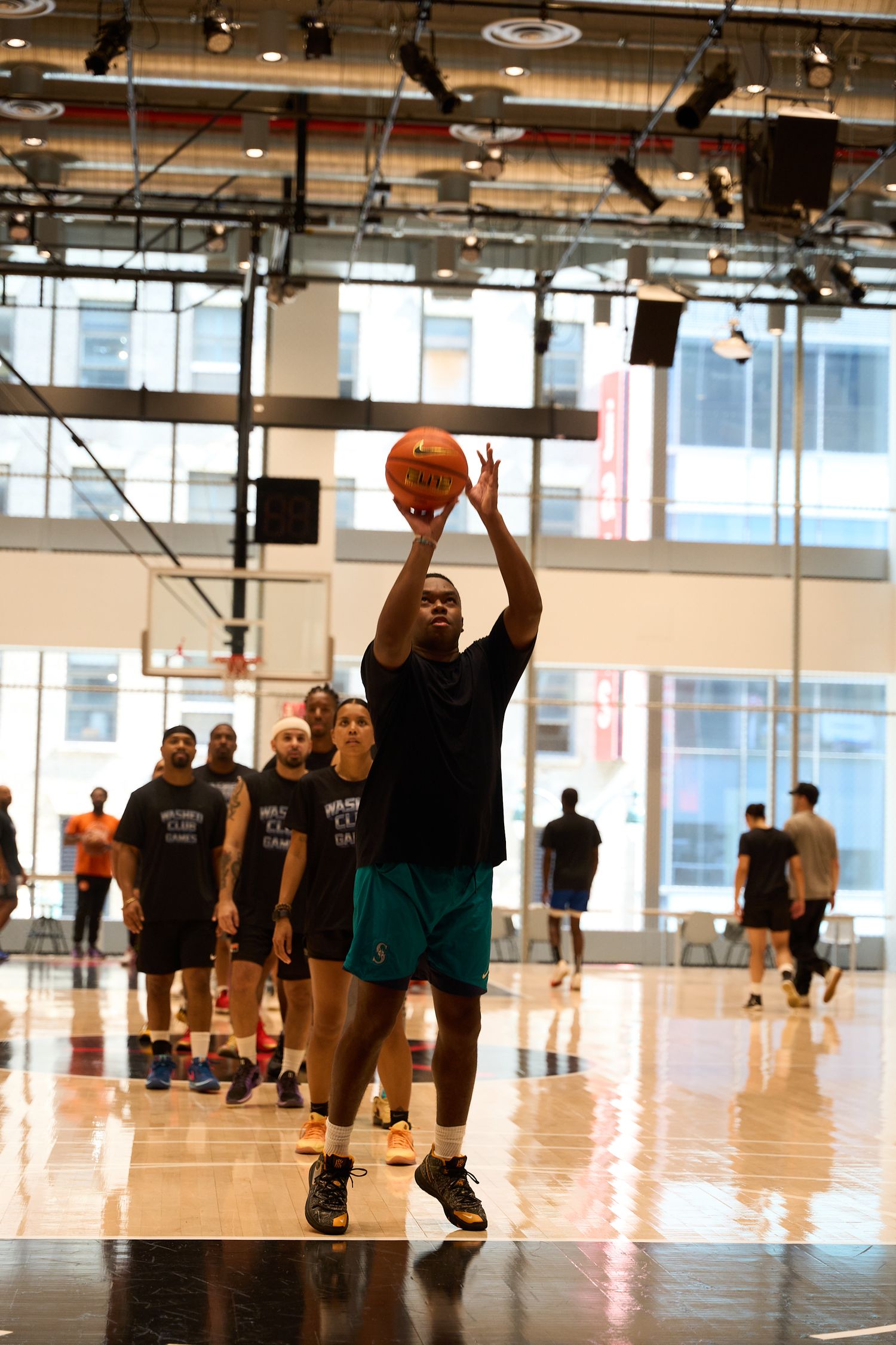 Players diving and sliding across a polished indoor basketball court during an intense training session.