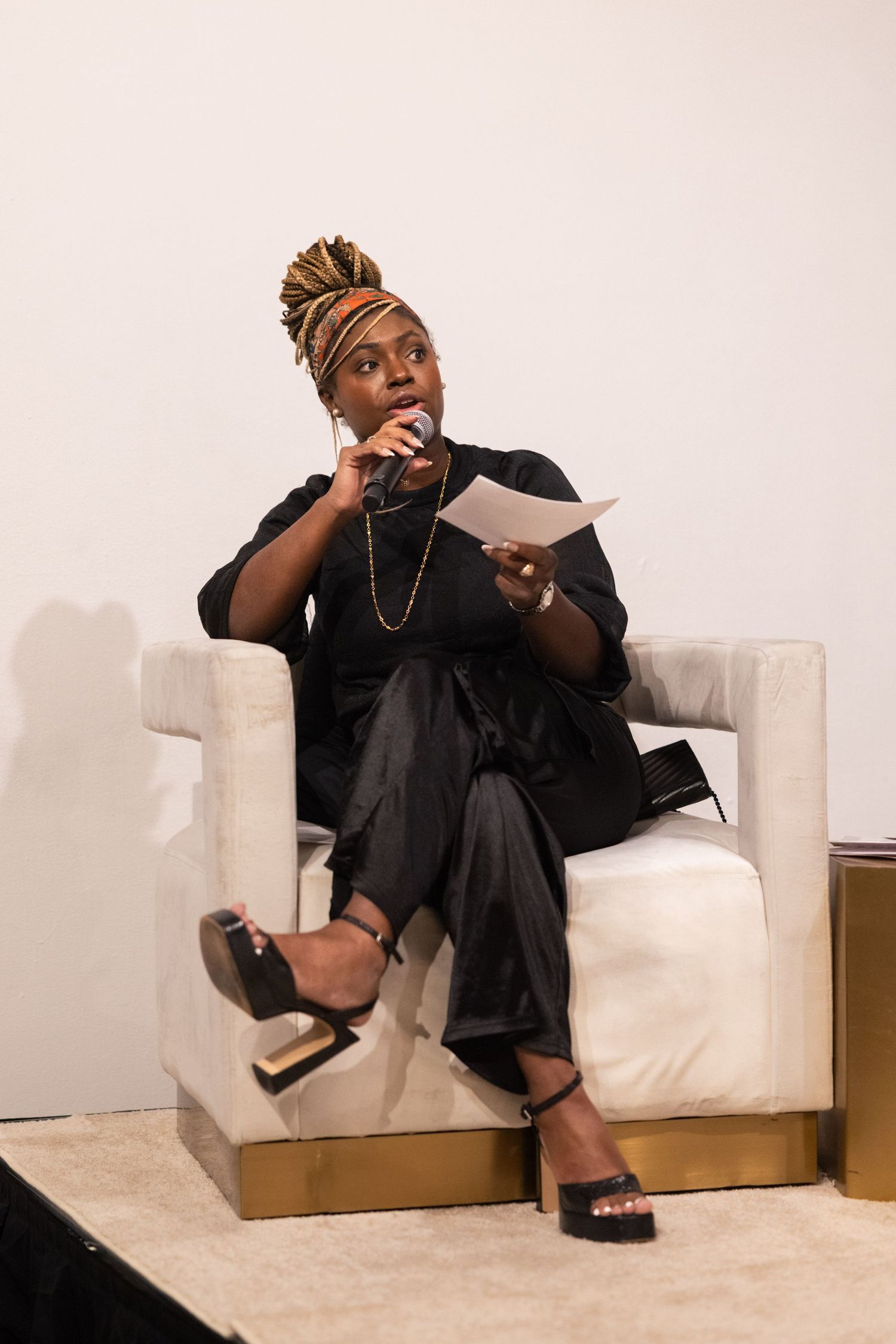 A person in black attire sits casually on a white couch, showing expressive gestures in a series of connected photos.