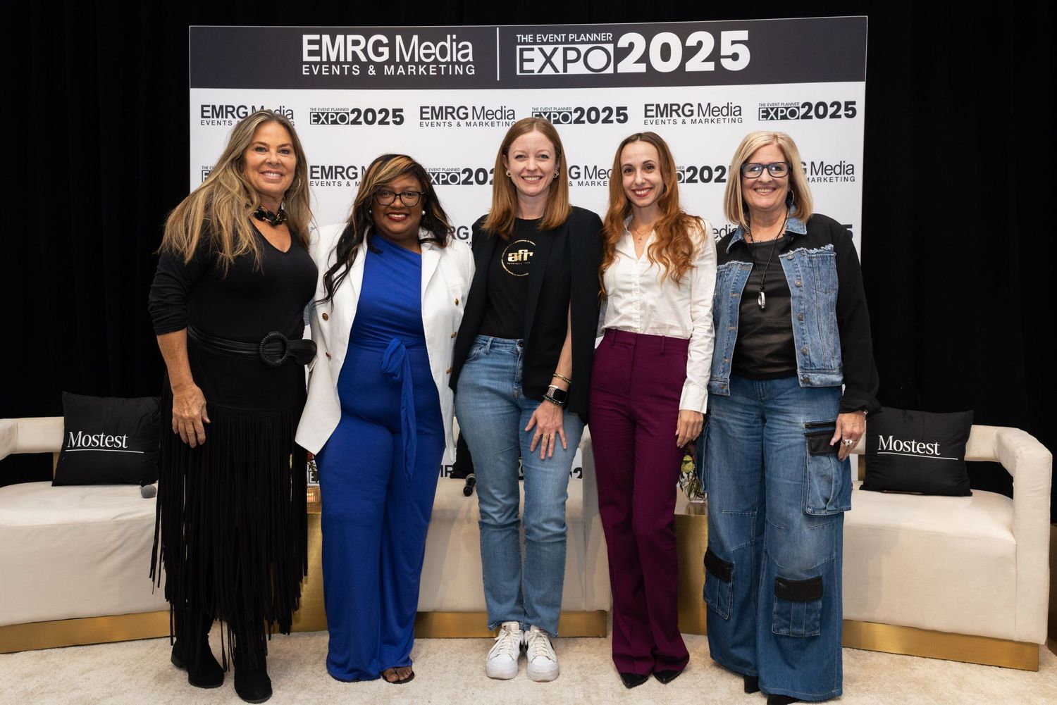 Group of attendees standing together at a conference with event banners and signage in the background.