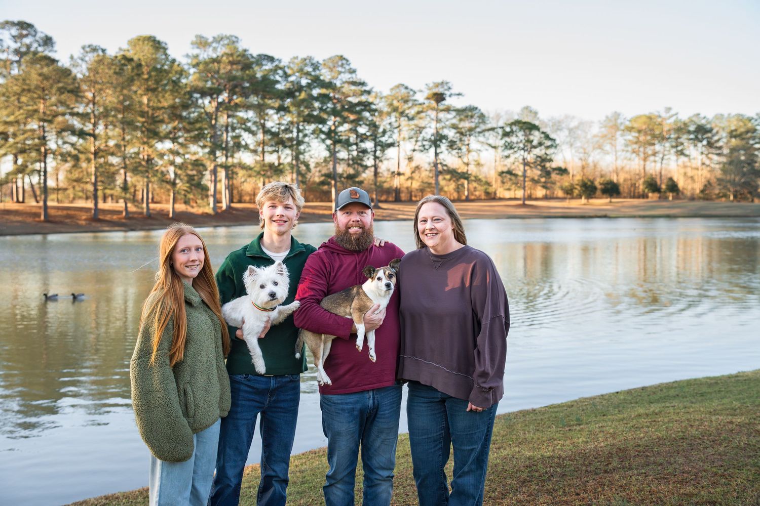 Family of four holding their two dogs during a morning dog photography session at a park in Perry, Ga