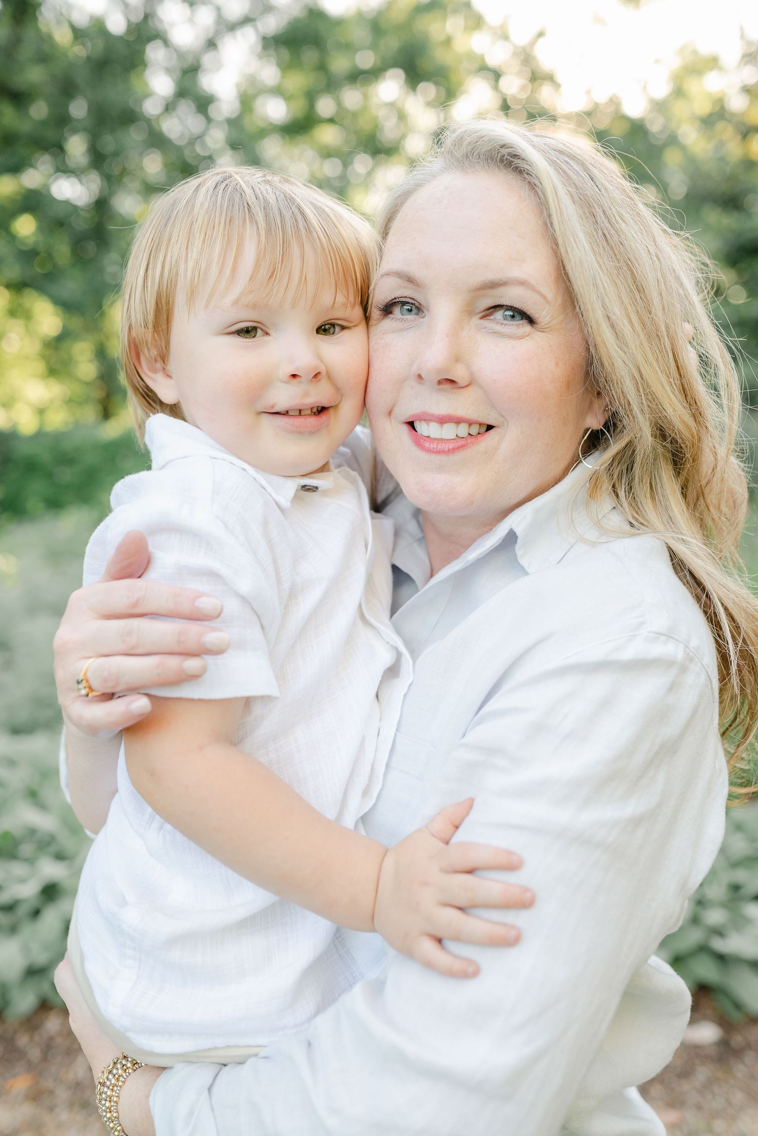 Outdoor family portraits showing tender moments between parent and child in white clothing.