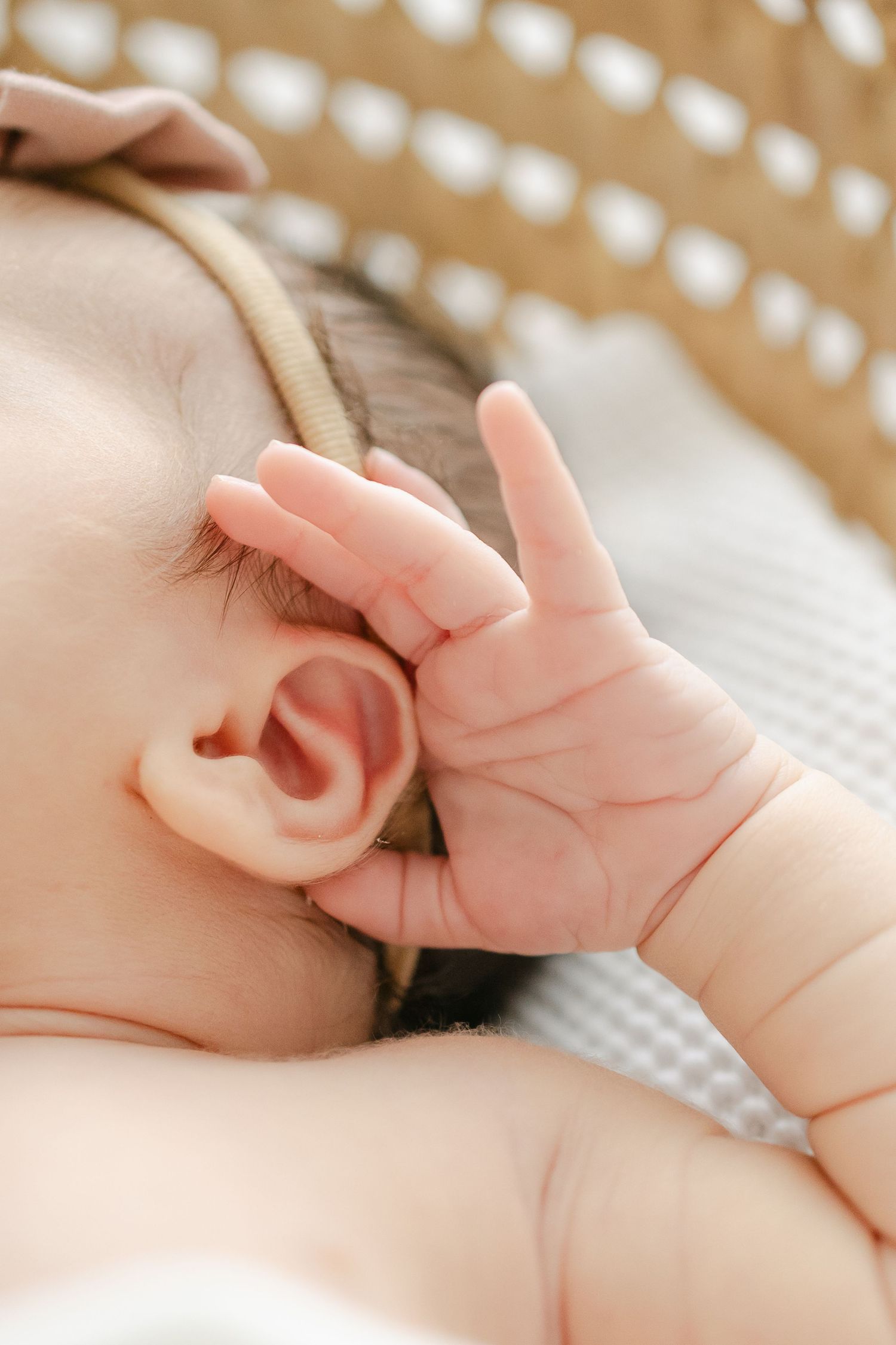 Close-up of tiny baby hand reaching up near ear.