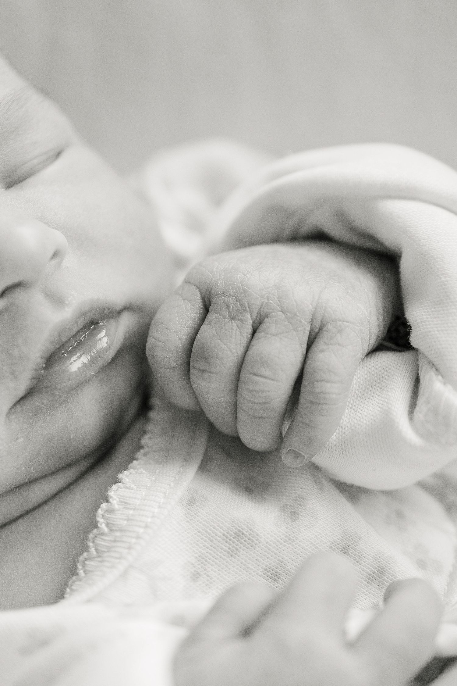 Close-up sequence of a baby's tiny hand grasping a white blanket.