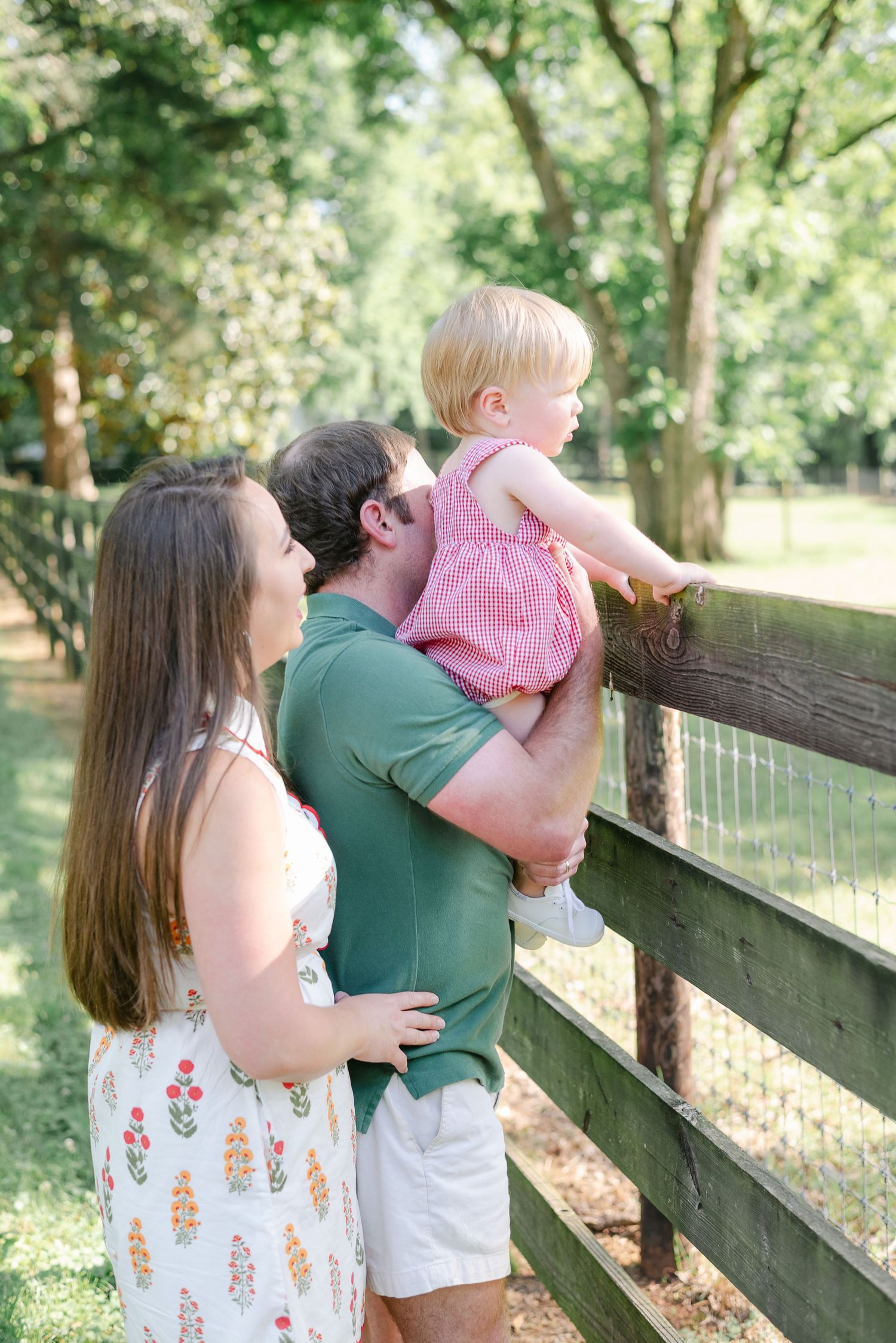 Family enjoying summer day by wooden fence in coordinated casual outfits.