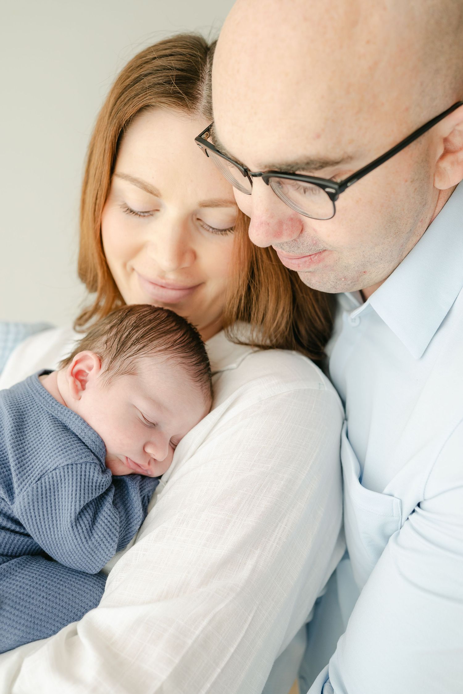Intimate family portrait showing gentle embraces and tender moments with a sleeping infant.