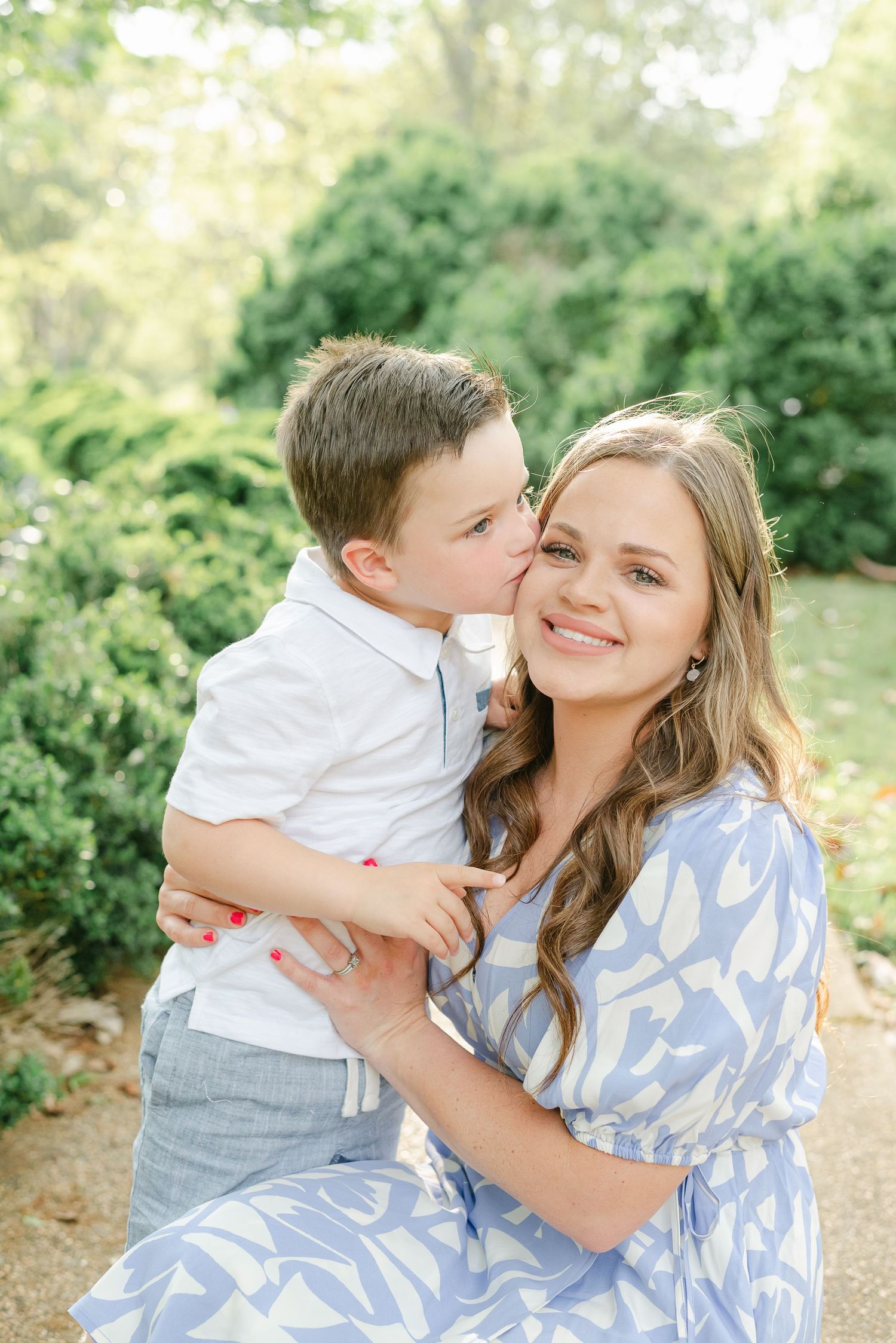 Sweet outdoor family moment captured in natural light among greenery.