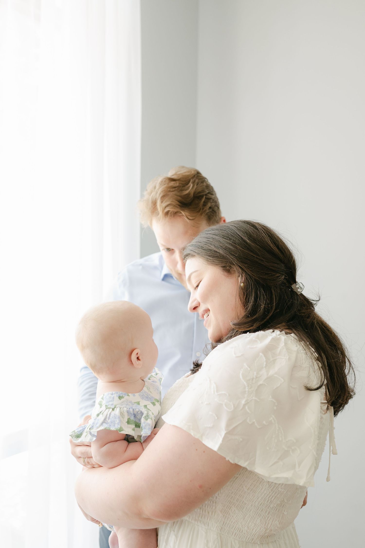 Tender family moment by window with soft natural lighting.