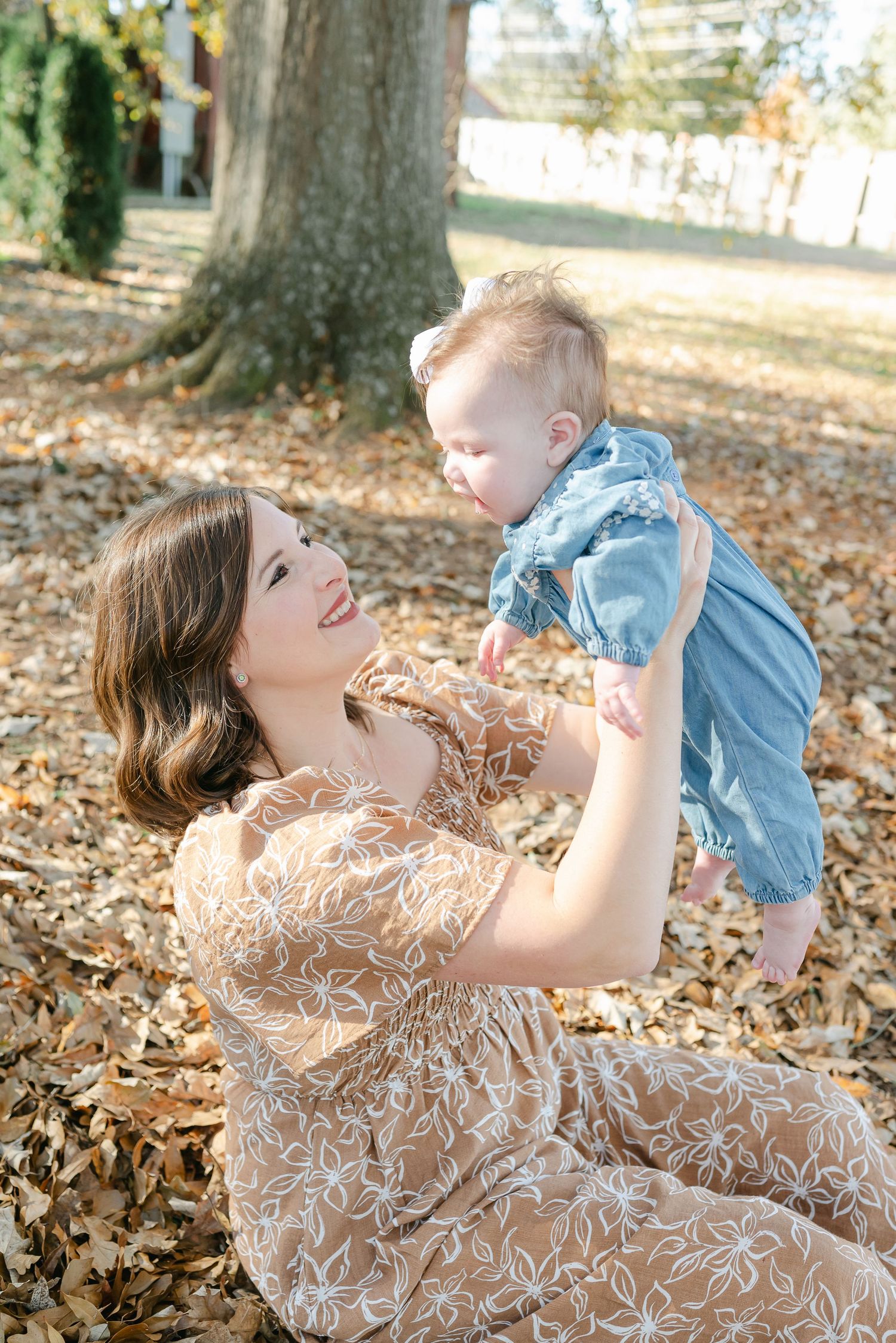 A tender moment captured in autumn as parent and child play together in fallen leaves on the ground.