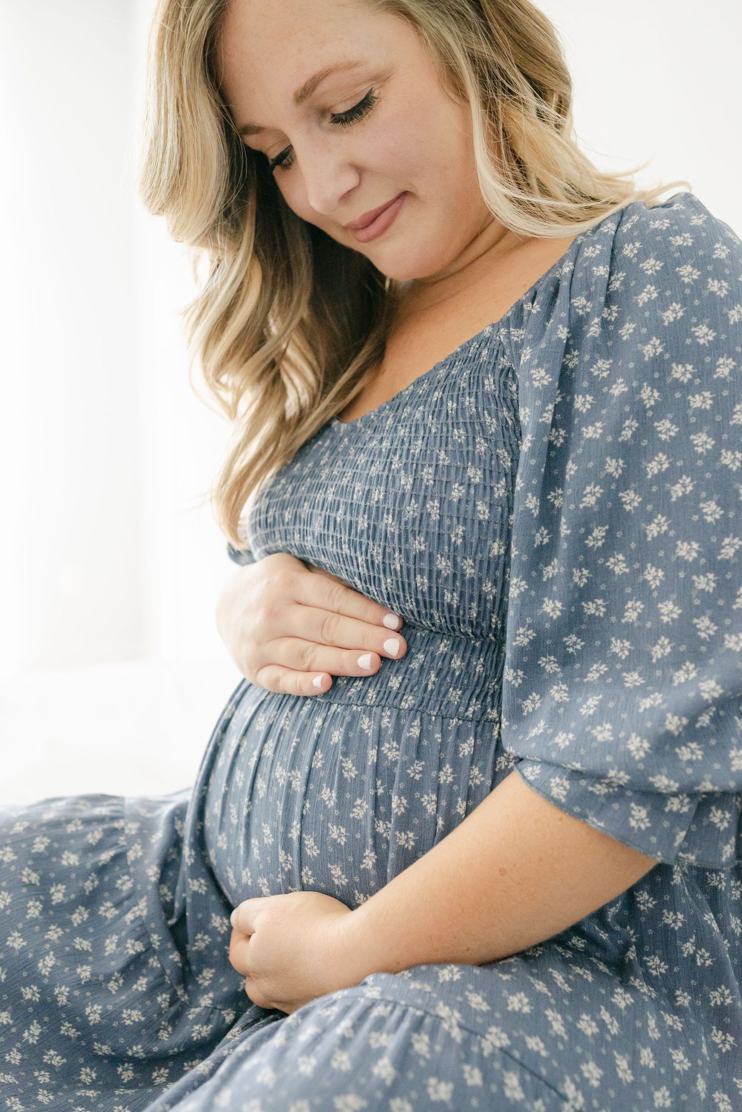 Close-up maternity photos in blue floral dress showing baby bump details.
