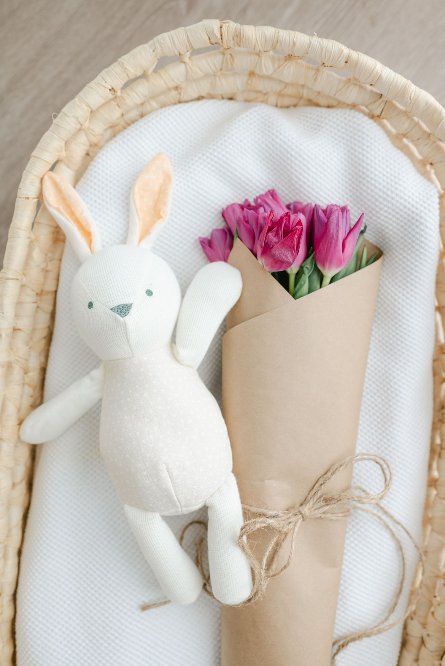 White plush bunny decorations arranged with pink flowers in a woven basket.