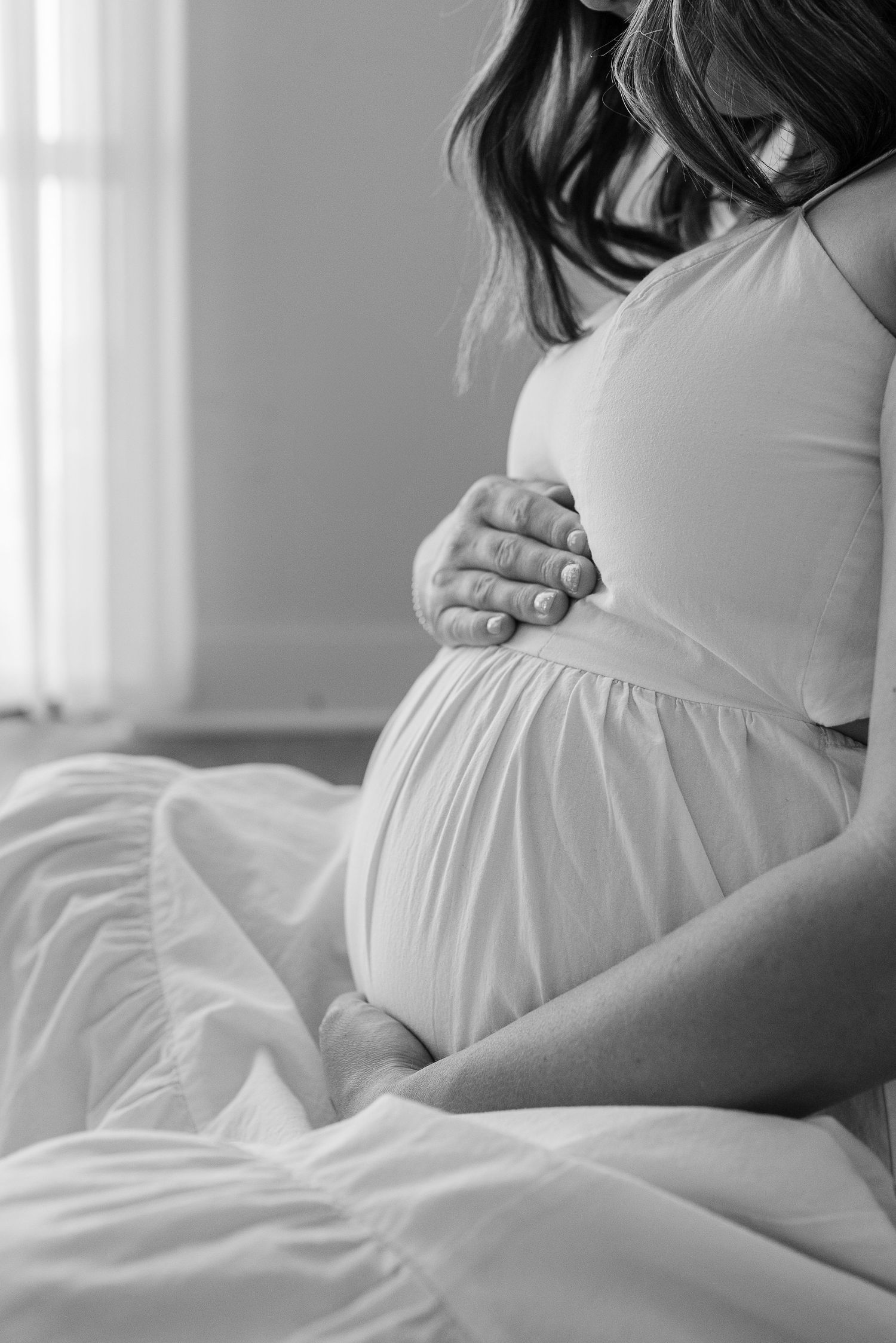 A black and white photo captures intimate maternity moments on a bed.