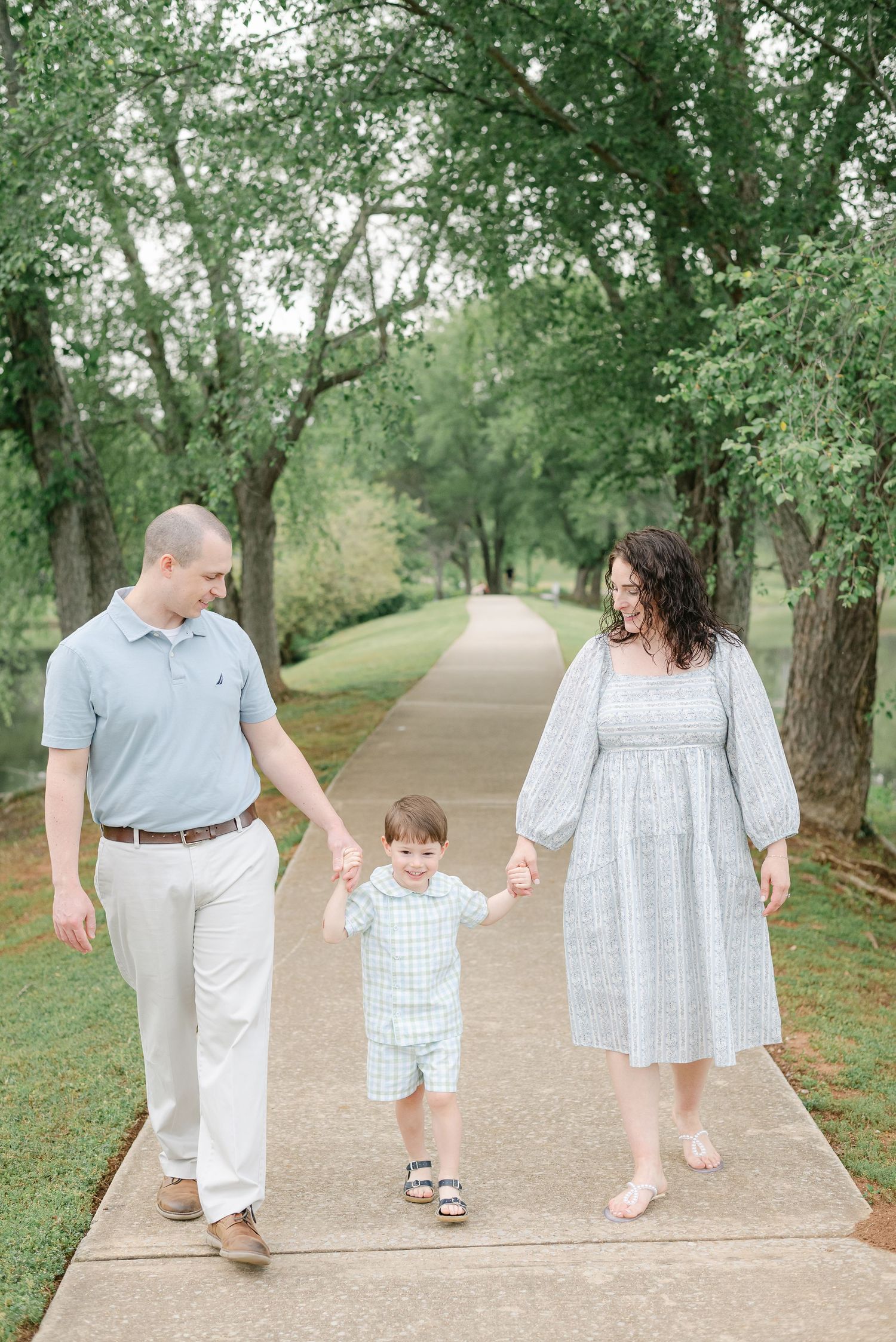 Family walks together on tree-lined path wearing coordinated blue and white outfits.