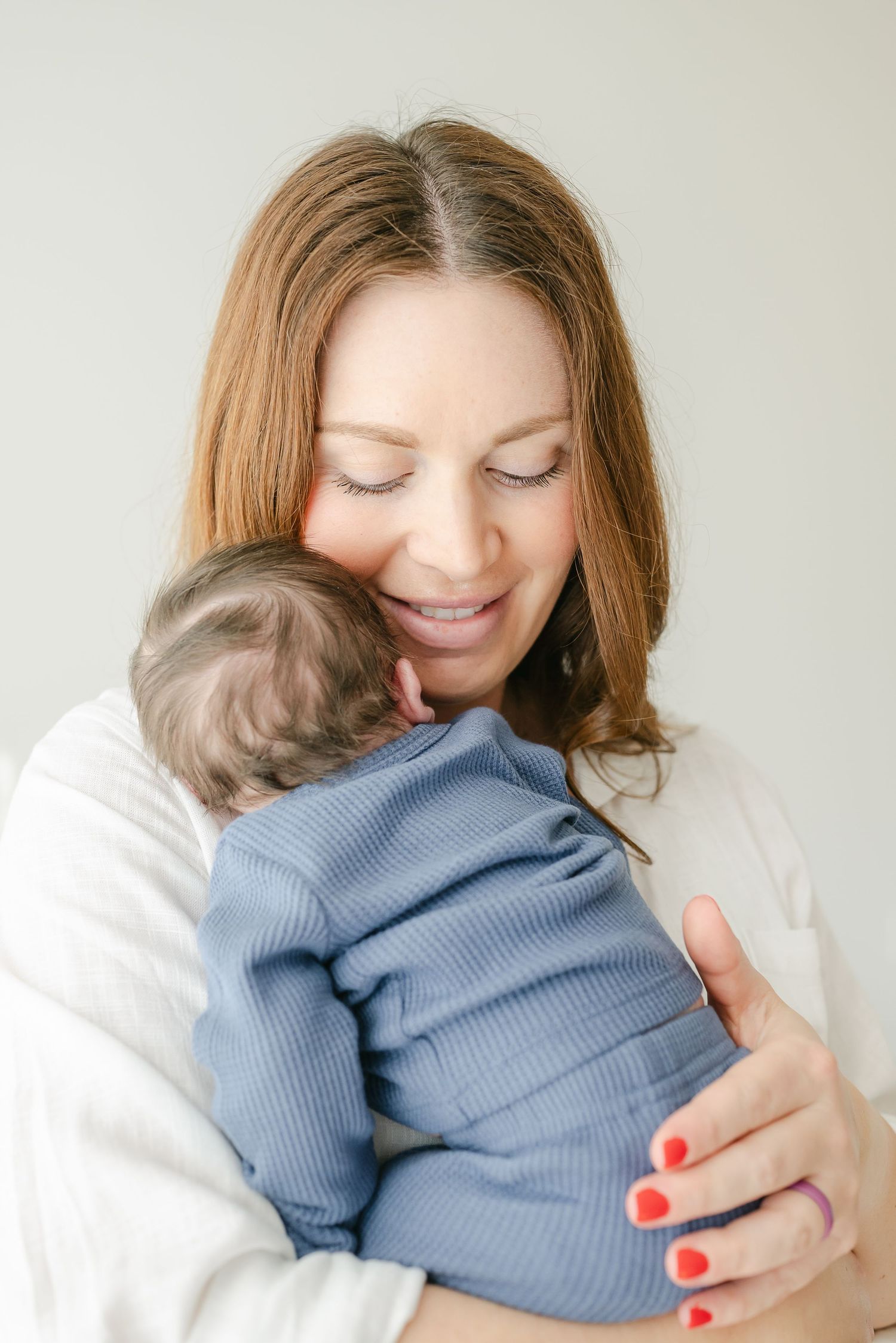 Mother embracing baby in blue knit sweater during studio photoshoot.