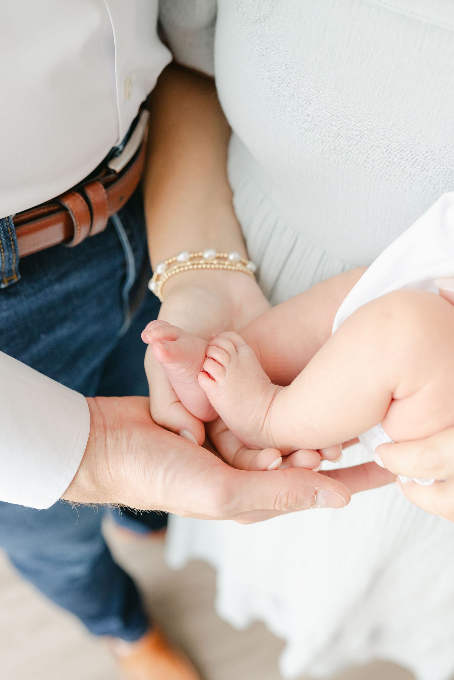 Close-up shots of tiny baby hands being gently held against a white background.